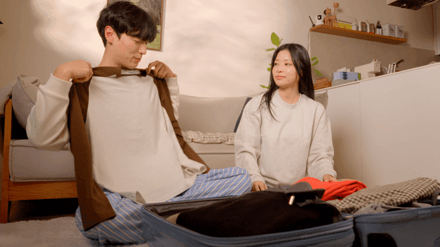 Affectionate couple packing clothes into travel suitcase