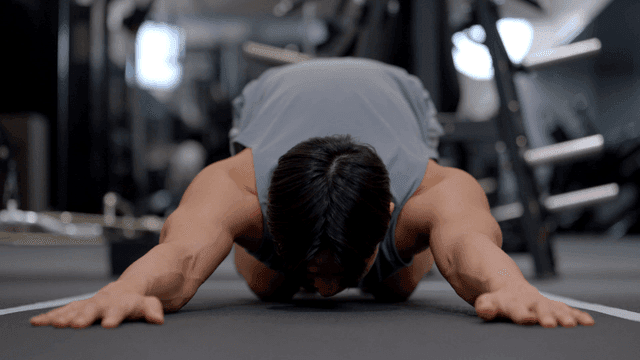 Young man stretching shoulders on gym floor