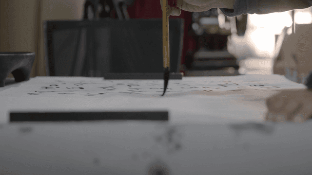 Person practicing calligraphy on rice paper