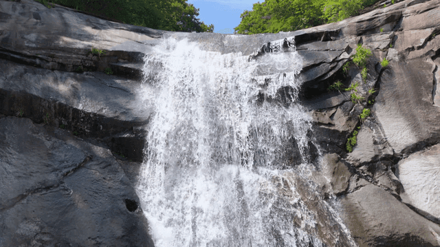 Refreshing waterfall flowing down rocky cliff