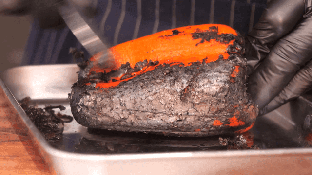 Burnt bell peppers being peeled on tray