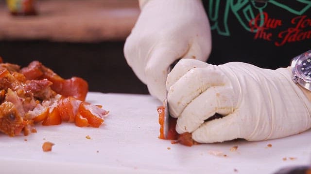 Cutting cooked pig trotters with a cleaver on a cutting board