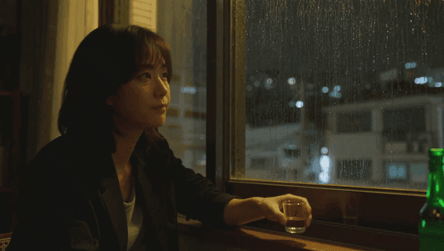 Woman drinking alone by a rainy window