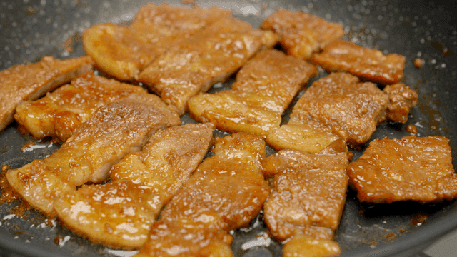 Marinated pork belly sizzling in a pan