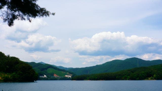 Serene lake surrounded by green hills under a cloudy sky