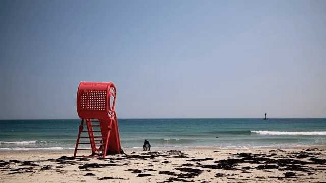 빨간 의자와 함께 해변에 앉아 있는 사람