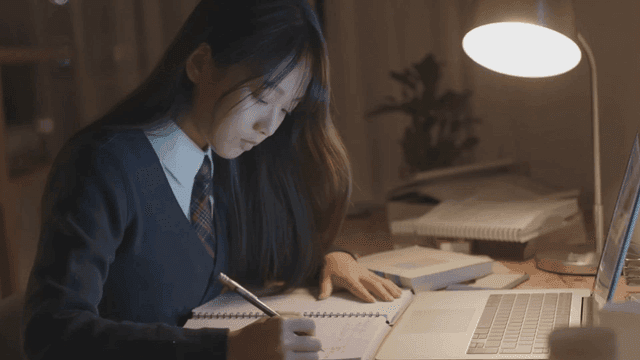 늦은 밤에 노트북이 있는 책상에서 공부하는 고등학생