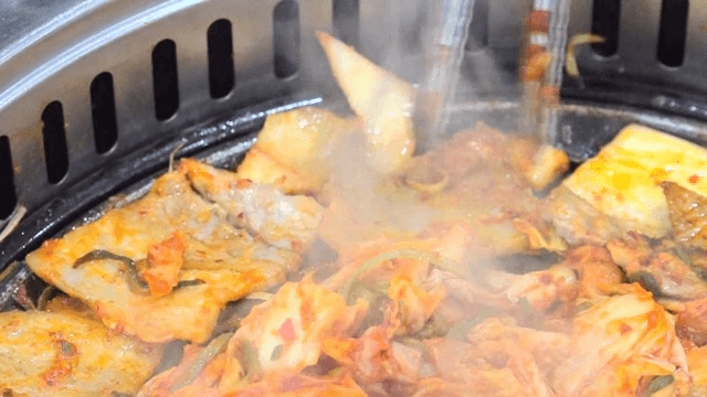 뜨거운 철판 위에서 김치와 돼지고기 굽기