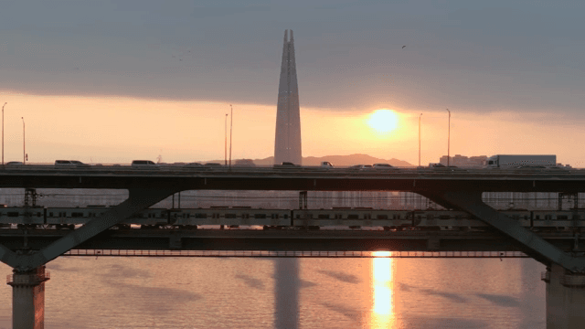 Train passing under a busy city bridge