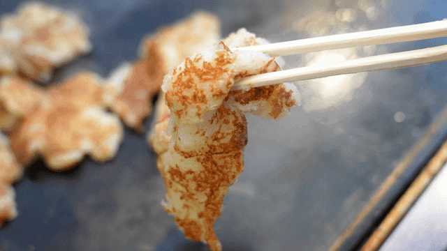 Sizzling potato pancake picked up with chopsticks