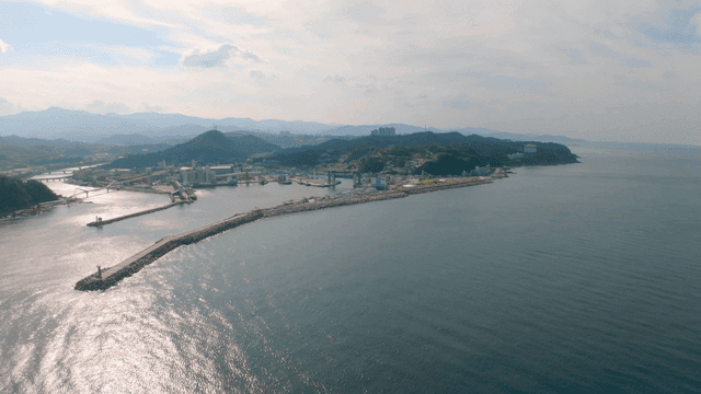 Wide sea in front of a coastal village beneath the mountain