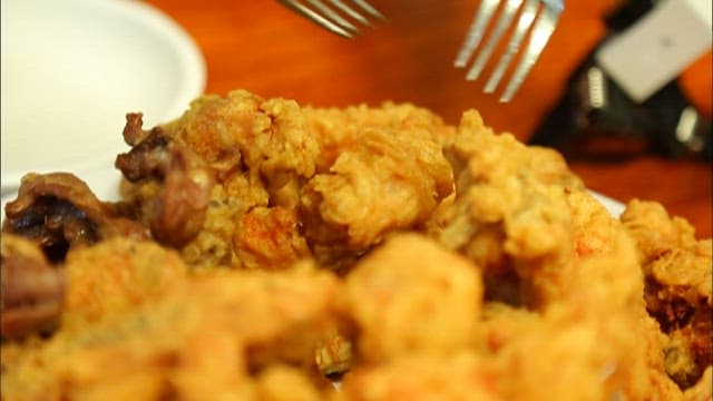 Fried chicken on a plate being picked up with a fork