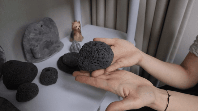 실내에서 다공성 검은 돌을 들고 있는 손