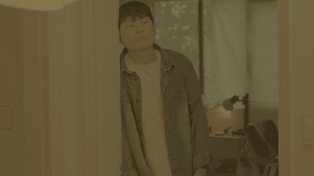 문틀에 기대어 웃는 남성