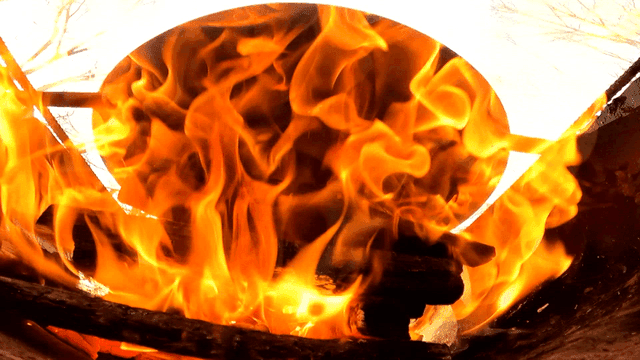 Burning firewood in hearth beneath pot