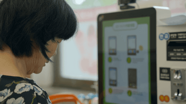 An elderly woman using a digital kiosk indoors