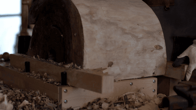 작업장에서 둥근 나무 조각을 검사하는 목공예가