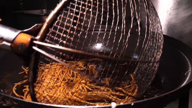 주방에서 웍으로 기름에 국수 튀기기