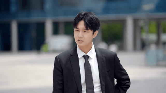 Man with a complicated expression in front of a building