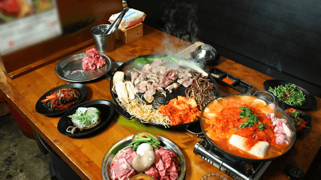 테이블 위의 한국식 돼지구이와 김치찌개
