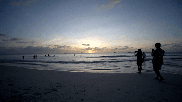 해변에서 일몰을 즐기는 사람들