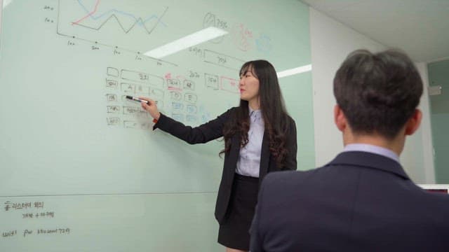 Woman in suit presenting on whiteboard in office