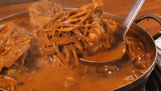 One ladle of pork backbone stew topped with sweet potato stems