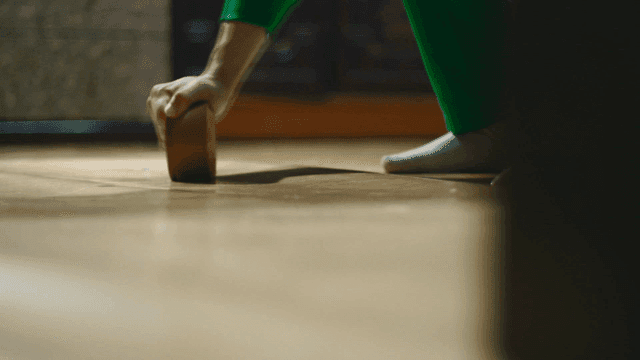 Person cleaning dust on floor with tape