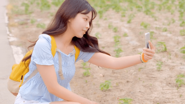 들판에서 사진을 찍는 젊은 여성