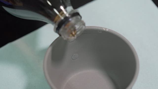 Pouring cola from a plastic bottle into a gray cup