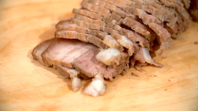 Slicing boiled pork slices on a wooden board