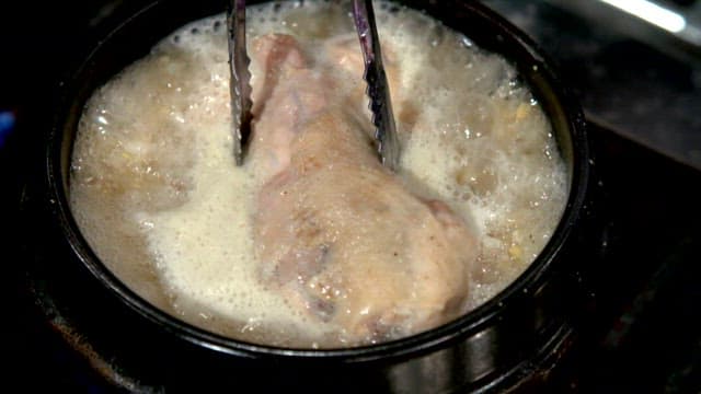 Chicken boiling in a pot with broth