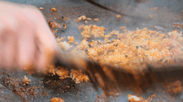 Sight of fried rice being cooked on cast-iron lid
