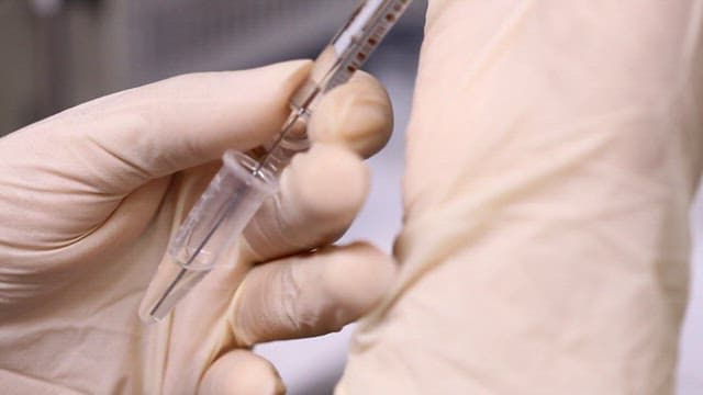 장갑을 끼고 주사기로 실험용액을 추출하는 모습