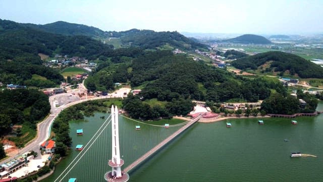 Scenic view of a mountainous landscape with a prominent bridge over a river on a sunny day.