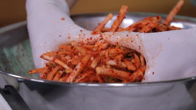 금속 그릇에서 무생채를 버무리는 모습