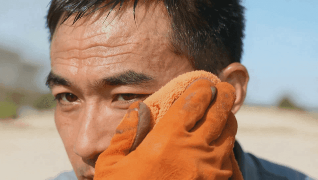 주황색 수건으로 땀을 닦는 남자