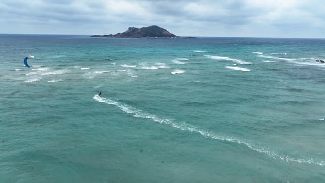 Kitesurfing on a turquoise sea with waves