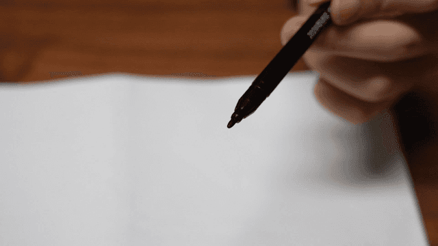 Hand holding computer marker pen on blank piece of paper