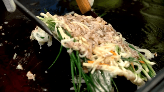 Seafood and green onion pancake flipped over on an iron plate