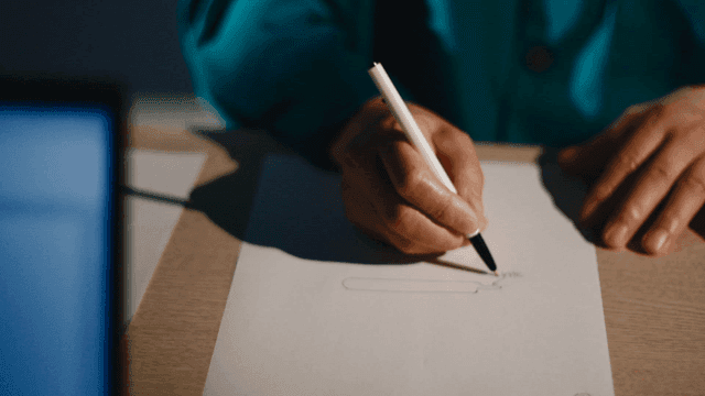 Prisoner drawing on paper with pen and laptop