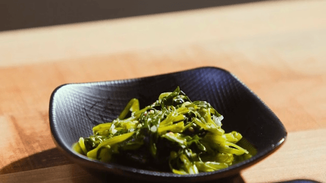 검은 접시에 담긴 시금치 무침