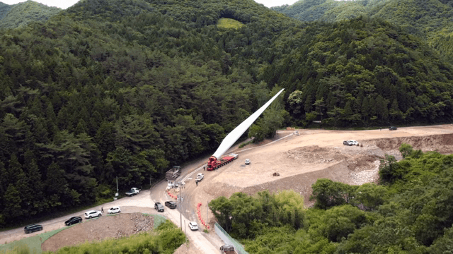 산 속 공사현장에서 풍력 터빈 자재를 운반하는 모습