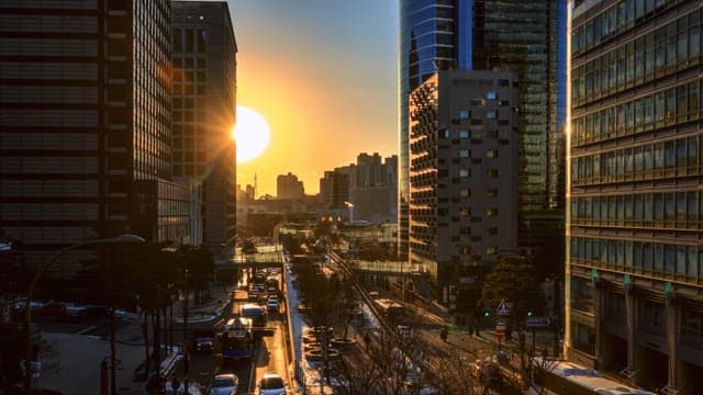 Busy city street at sunset with high-rise buildings and street lights glowing