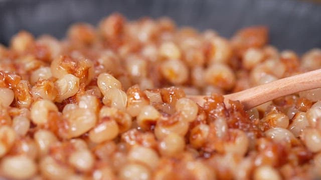 프라이팬에 볶은 옥수수를 나무 숟가락으로 뜨는 모습