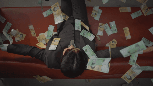 소파에 앉아 돈을 뿌리는 남성