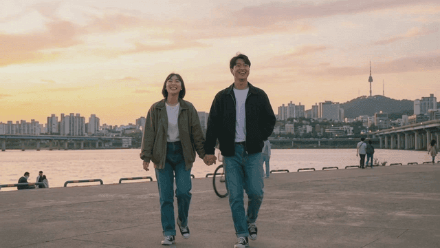 Couple walking in riverside park at sunset