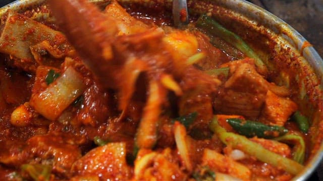 Mixing the spicy braised ribs with plenty of vegetables using a spoon