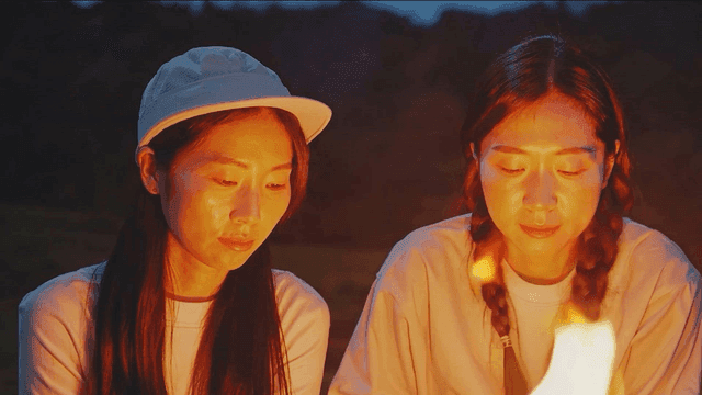 Two friends enjoying a campfire at night
