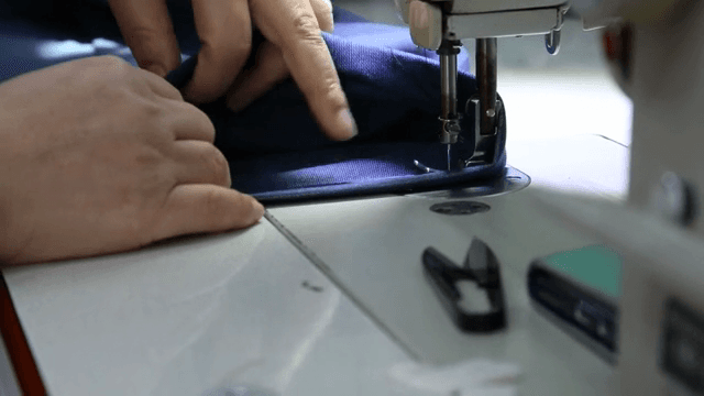 재봉틀로 천을 바느질하는 손